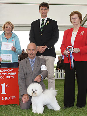 Mr M Coad Regina Bichon Zoom To The Moon at Pamplona (Imp) with puppy group judge Mrs S M Marshall, Mr B Hanney (Committee) & J Buttle (Plush Puppy)